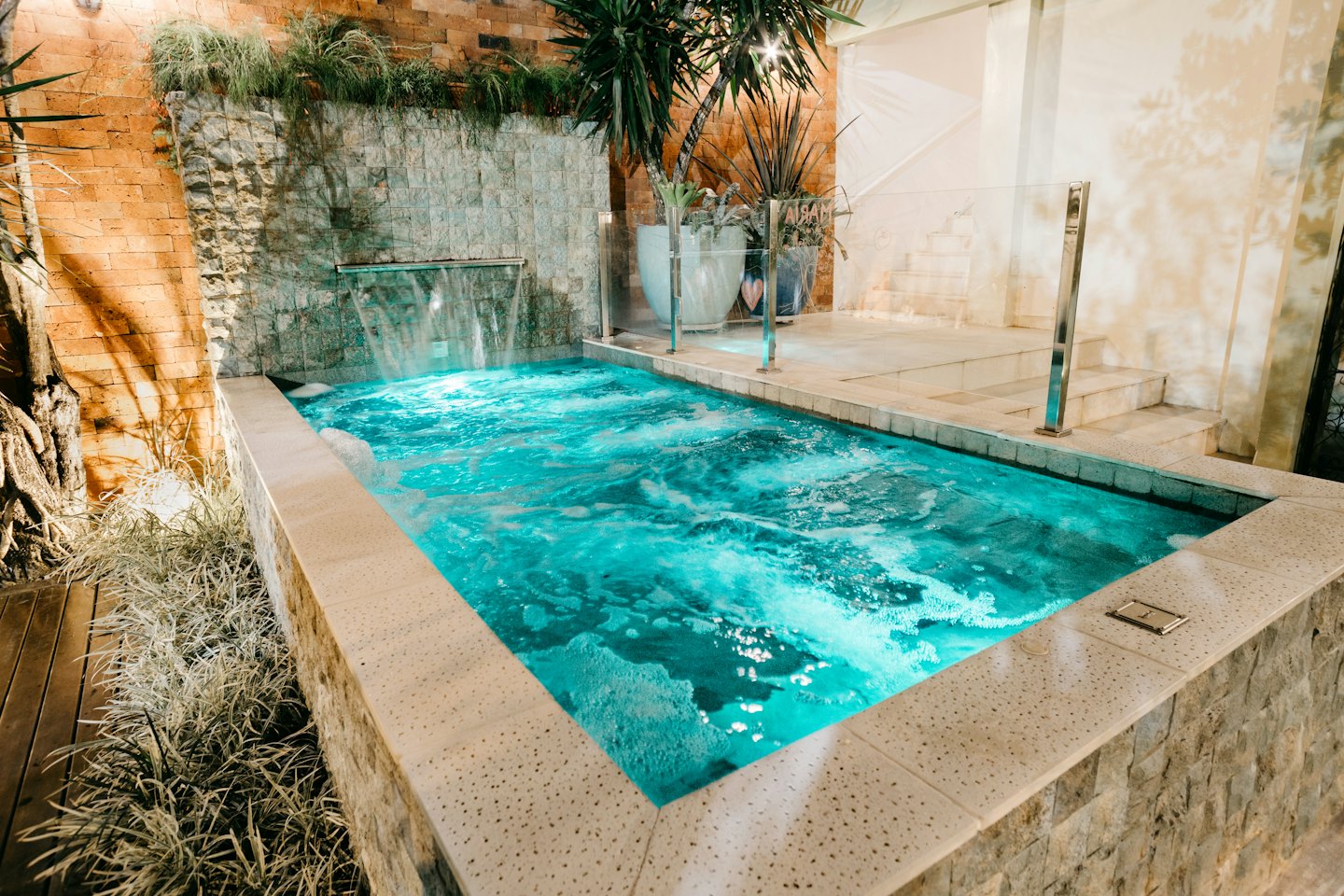 Bubbling outdoor hot tub with a waterfall on a stone patio.
